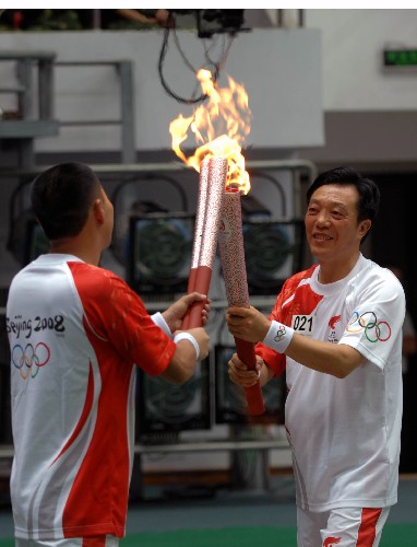 8月4日,火炬手李先荣(右)与下一棒火炬手赵冲进行交接.