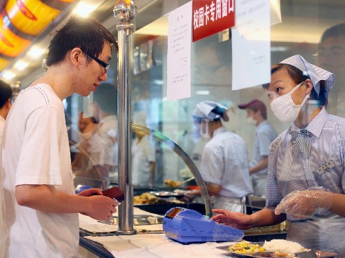     9月4日,在上海交通大学学生食堂内,学生正在打饭.