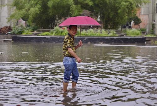 5月9日,行人挽起裤腿行走在南昌市迎宾大道一处积水路段.