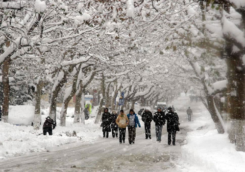 2005年12月18日,行人走在大雪纷飞的威海市街头 新华社发(朱春晓 摄)