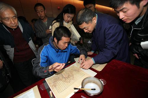 4月23日,国家图书馆的工作人员现场指导读者学习古籍修复的技艺。当日是世界读书日,北京国家图书馆举行中国非物质文化遗产技艺互动展演,现场展示了中国各个时代的雕版,还向读者演示了雕版印刷、甲骨和石碑传拓、古籍修复和装订等技艺,吸引了众多读者参与。新华社发(陈晓根 摄)