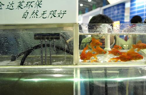 11月18日,参观者在博览会上观看一款低耗能的污水处理系统。左下角的缸内是污水,经过右下角的设备净化,过滤后的水可以重新使用,甚至可以饲养金鱼。11月17日至21日,低碳与生态技术博览会在南昌举行,3000多个展位全面展示了近年来国内外在环保、节能减排、科技创新等领域的各项成果,使公众体验到“低碳”生活的魅力。新华社发(周密 摄)