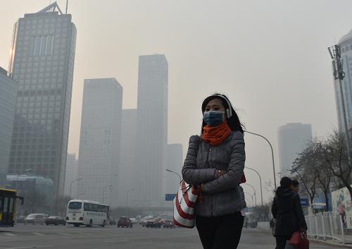 11月28日，一名戴口罩的行人在雾霾下的北京街头行走。当日，北京出现重污染天气。