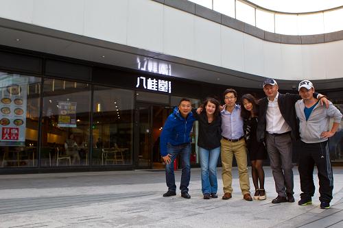 张高山（右二）和他的创业团队成员在位于北京望京SOHO的一家名为“八桂堂”的桂林米粉店前合影（10月3日摄）。这是一家由31名广西老乡众筹投资、共同经营的桂林米粉店，9月28日开张迎客当天卖出了500碗米粉，且供不应求。