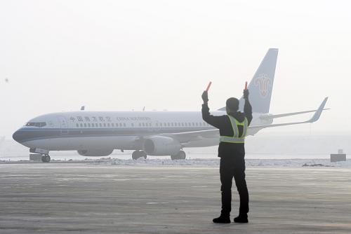 12月26日，一位地勤人员引导刚刚降落在石河子花园机场的飞机进入停机坪。