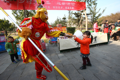1月1日，在浙江省奉化市萧王庙街道滕头村大集上，一名小朋友和“美猴王”互动。新华社发（张培坚 摄）