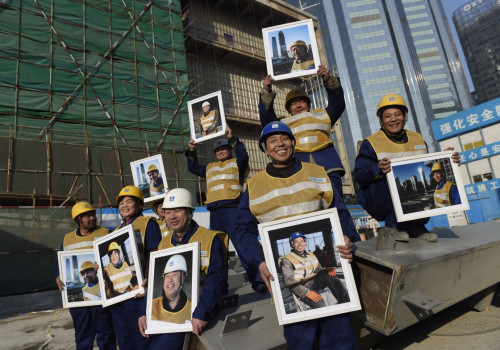 1月14日，在中国国际贸易中心三期的建设工地，劳动者展示自己的照片。当日，中建一局的100位劳动者领到了免费肖像照，这是“把微笑带回家，为最美建设者点赞——关爱在京外来务工人员”大型公益活动的一部分。肖像照是由摄影俱乐部和摄影志愿者免费为他们拍摄，并印制成照片。本次活动由劳动午报社、北京市劳动模范协会、北京工会传媒协会主办。新华社记者 李文 摄