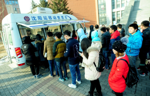 1月14日，在沈阳农业大学，学生们在铁路移动售票车前排队购票。新华社发（张文魁 摄）
