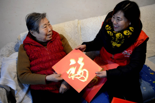 1月28日，洛阳市居家养老服务中心的工作人员张艳英到杨慧琛老人家中回访并送上对联和门贴。新华社记者 朱祥 摄