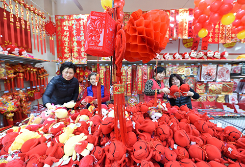 1月29日，在南京沃尔玛超市新开设的汇聚了4000多种春节商品的“年货一条街”购物区，几位市民在选购装饰品。