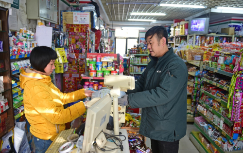 2月7日，中国邮政集团公司沈阳皇姑区分公司的投递员（右）将包裹送到客户手中。当日是农历除夕，不少行业的工作人员依然坚守在自己的岗位上，在工作中度过假期。新华社记者 杨青 摄