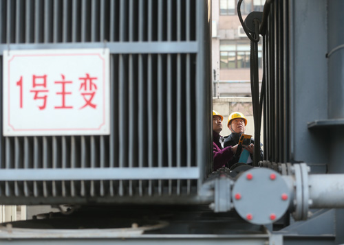 2月7日，国网上海市南供电公司的工作人员周志浩（右）和顾轶旻在变电站内巡视，记录变压器运行数据。