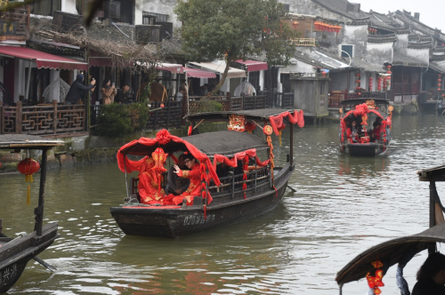 2月12日，浙江西塘古镇举办水乡婚礼巡游表演，“新人”向岸边的游客招手致意。新华社记者 黄宗治 摄