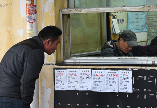 2月13日，一名求职者（左）在安德门民工就业市场的职介窗口旁看招聘广告。
