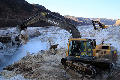 2月16日，山西吉县黄河壶口瀑布景区工作人员用挖掘机铲除堆冰。