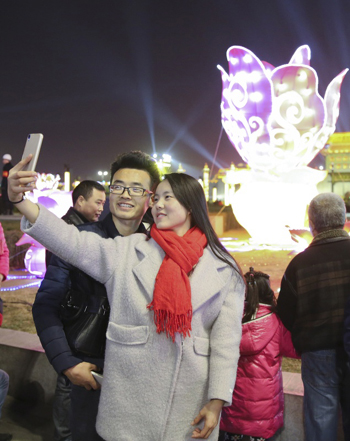 2月19日，游客在彩灯装饰下的西安南门文化广场上合影留念。新华社发（邵瑞 摄）