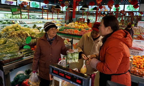 2月25日，北京海淀区中关村街道的老人在“车客家园”社区服务店购买便宜新鲜的蔬菜。