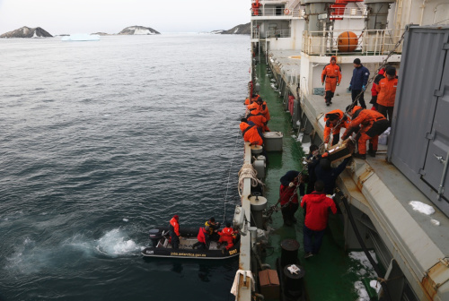 3月8日，戴维斯站将2名需要搭乘“雪龙”号回澳大利亚的考察队员通过小艇运送至“雪龙”船边。当日，“雪龙”号抵达澳大利亚南极考察站戴维斯站，接运由于澳大利亚“南极光”号破冰船搁浅而滞留戴维斯站的2名澳方科考队员，以及50余件需要及时运回的珍贵样品等物资。这是中国第32次南极科考队第3次向澳方提供协作和支援。新华社记者 朱基钗 摄