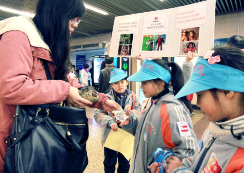这是2012年12月29日在上海拍摄的一位市民（左一）在“蓝天下的至爱”——“我们的年轻范·为了孩子”万名志愿者冬日阳光青春温暖劝募行动中捐款的资料照片。新华社记者 丁汀 摄