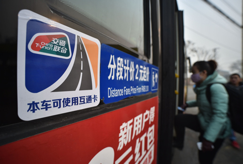 乘客在北京焦化厂公交站乘坐贴有“交通联合”标识的公交车（2015年12月20日摄）。京津冀交通一卡通互联互通卡（简称“互通卡”）用于京津冀交通领域互联互通，卡面标有“交通联合”标识。
