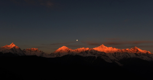 这是3月25日清晨拍摄的梅里雪山“日月同辉”景观。梅里雪山位于滇藏交界的云南省迪庆藏族自治州德钦县境内，是世界自然遗产“三江并流”的主要自然景观之一。梅里雪山常年云雾笼罩，太阳光只在少数天晴的清晨照射在雪山顶上，形成绝美的“日照金山”美景。有时月亮尚未落山，太阳已经升起，更是形成了难得一见的梅里雪山“日月同辉”奇观。新华社记者 王长山 摄
