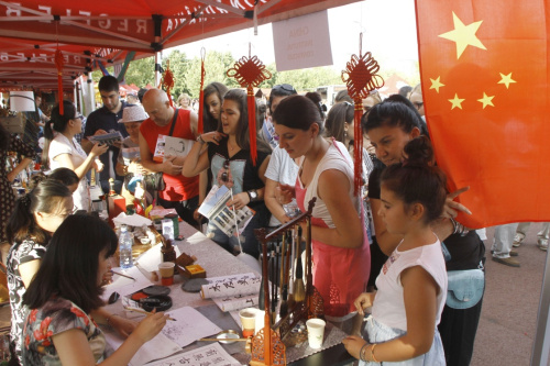 2015年9月5日，在罗马尼亚首都布加勒斯特举行的首届大使馆节上，人们在中国展台等待领取写着自己中文名字的书法作品。本届大使馆节由罗马尼亚外交部主办，是展示各国文化的活动。新华社发（佩特雷斯库 摄）