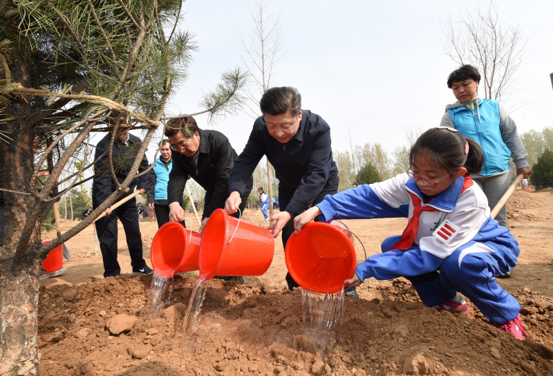 这是习近平同大家一起给刚栽下的树苗浇水。新华社记者 李学仁 摄