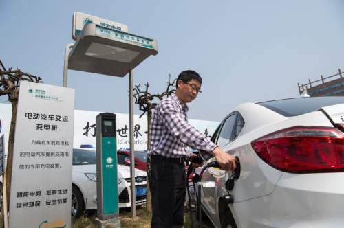 3月18日，一名车主在重庆市内一处停车场使用国网重庆市电力公司的充电桩为新能源电动汽车充电。新华社记者 刘潺 摄