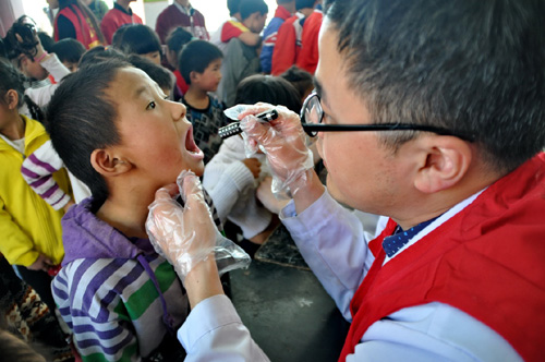 4月9日，医务志愿者在为留守儿童检查口腔。