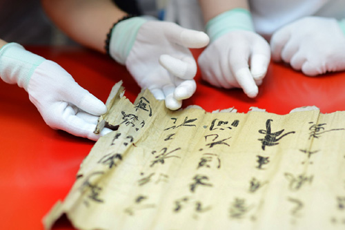 2013年7月15日，在天津博物馆，2013年全国纸质文物保护修复技术培训班学员在专家指导下展开受损的古旧字画。