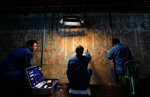 2014年9月3日，三名技术人员在敦煌莫高窟98窟内对病害壁画进行修复。