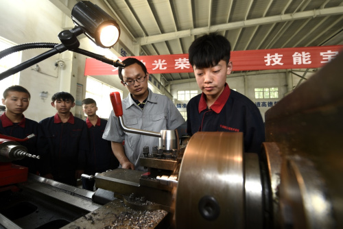5月18日，平遥现代工程技术学校机械技术专业的学生在练习车工操作。今年全国两会上，“工匠精神”被写入政府工作报告。为学生注入“工匠精神”，正成为很多职业中学的努力方向。在山西晋中，太谷职业中学、平遥现代工程技术学校等农村职校探索专业、专注、精准、创新和个性化的培养理念，一方面提升学生职业能力，一方面提升学生职业素养，重“传技”更重“育人”；同时通过“技能大师进校园”“技能展示周”“现代学徒制”等特色教学方式让学生形成职业情感，理解“工匠精神”的内涵与价值。新华社记者 燕雁 摄