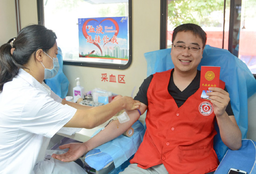 6月14日，河北衡水市民韩磊在一辆街头流动献血车上参加无偿献血。