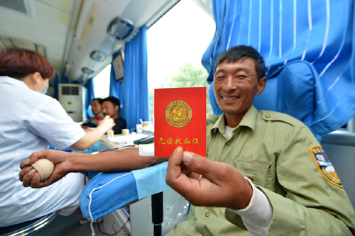   6月14日，河北省深州市市民在流动献血车内献血时展示无偿献血证。