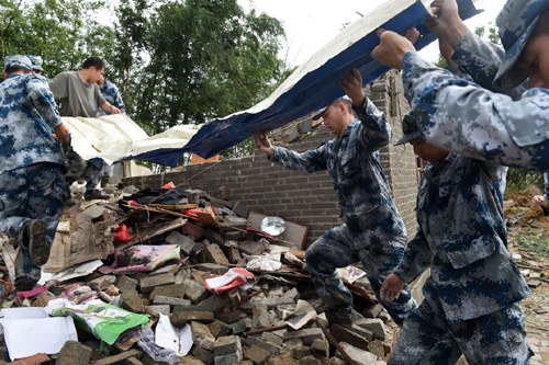 6月24日，驻地空军某部官兵在盐城阜宁县陈良镇丹平村一受损房屋前进行清理工作。