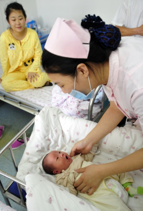 7月12日，宣城市妇女儿童医院护士龚琴在病房中为灾区产妇陶海蓝（左后）和她出生仅13天的宝宝体检。这名宝宝由于早产患上新生儿黄疸，经医务人员精心治疗，已基本痊愈。记者 王雷 摄