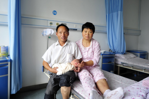 7月12日，沈村镇胜利村村民杨建平（左）、吴天娥在宣城市妇女儿童医院特护病房与他们出生仅5天的“洪水宝宝”拍下一张全家福。记者 王雷 摄