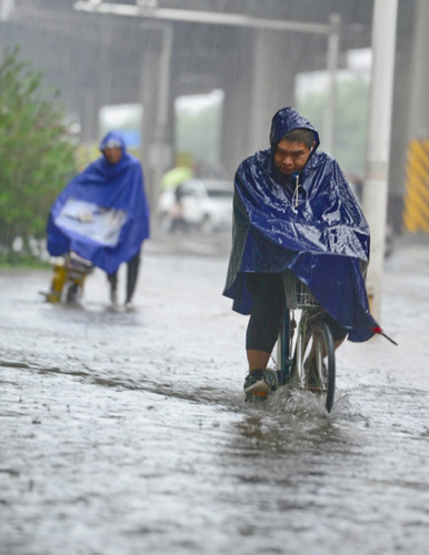 7月20日，一位石家庄市民在槐安路冒雨涉水骑行。