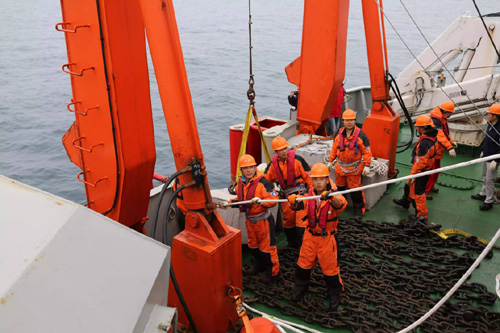 7月19日，科考队员和船员将固定浮标的锚链和锚绳放入海中。