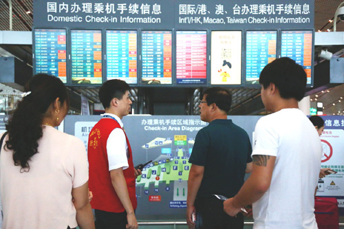 7月20日，在北京首都机场，工作人员向旅客解释航班信息。