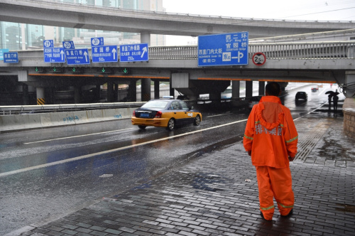 7月20日，一名北京排水集团工作人员在西直门桥附近监测积水情况。当日，北京排水集团应急抢险大队在暴雨中进行监测与排水工作。当日11时30分，北京市气象台发布暴雨橙色预警，目前城区及南部地区6小时累计降水量达70毫米左右，局地超过100毫米，预计至20日傍晚强降水持续。记者 李鑫 摄