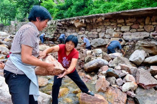 8月6日，河北省沙河市柴关乡阴河沟村村民在垒筑被洪水冲毁的道路。记者 牟宇 摄