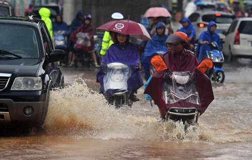 8月18日，市民在海口市南沙路涉水骑行。