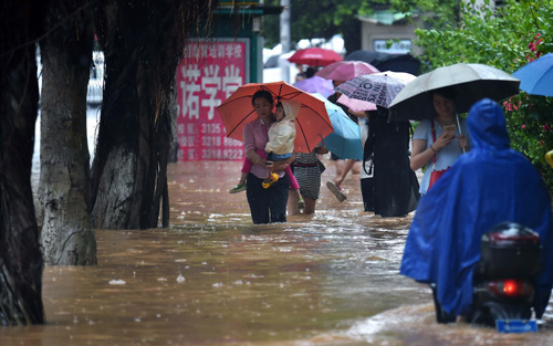 8月18日，市民在海口市龙昆南路涉水前行。