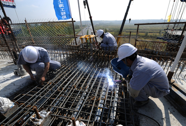 9月25日,工人在哈佳铁路哈尔滨特大桥跨环城高速连续梁主跨合龙处施工。