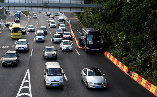 10月24日，一辆可自动“吞吐”道路隔离带的潮汐车道“拉链车”（最右）在深圳布吉路作业。