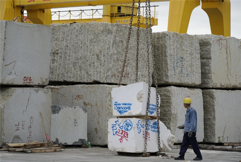 工人在福建省南安市水头镇康利石材集团的荒料场准备吊运石材荒料