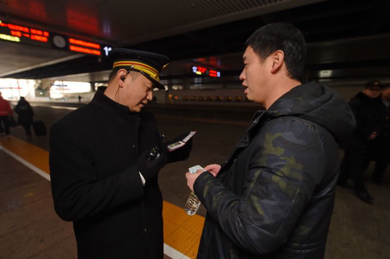 12月14日，沈阳铁路局长春客运段动车队哈大高铁列车长高昌华（左）为旅客验票。截至今年12月1日，我国首条高寒高铁——哈大高铁（哈尔滨到大连）已连续安全运营4周年，累计发送旅客1.4亿人次，安全高效开行动车组列车262958列。新华社记者 张楠 摄
