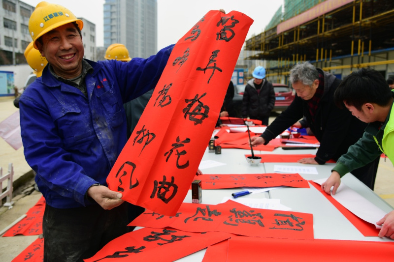 1月10日，一名外来务工人员在展示志愿者为他书写的春联。