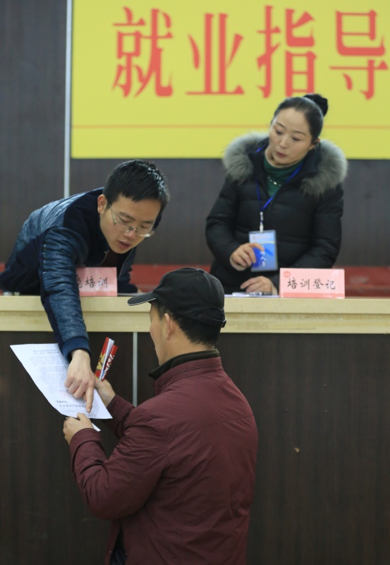 2月15日，在咸阳市体育馆，工作人员在“就业援助月”活动咸阳会场向务工者讲解针对当地农民的免费技能培训政策。